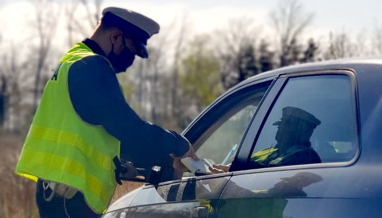 zdjęcie kolorowe: policjant ruchu drogowego podczas kontroli pojazdu