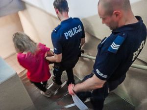 Zatrzymana kobieta prowadzona  przez policjantów