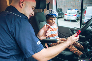 Policjanci pokazują radiowóz małemu chłopcu