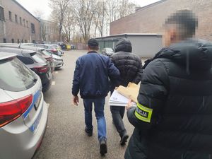 Na zdjęciu policjanci prowadza zatrzymanego