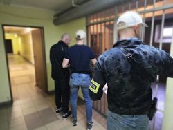 na zdjęciu policjanci prowadza zatrzymanego