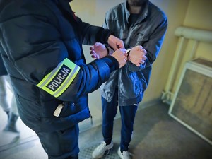 na zdjęciu policjant zakłada kajdanki zatrzymanemu