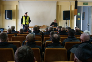 Policjant z wydziału ruchu drogowego prowadzi szkolenie dla strażaków.