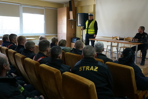 Policjant z wydziału ruchu drogowego prowadzi szkolenie dla strażaków.