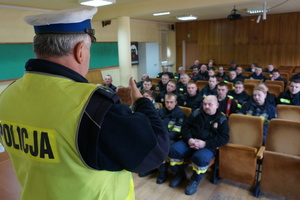 Policjant z wydziału ruchu drogowego prowadzi szkolenie dla strażaków.