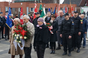 Delegacje składające wiązanki kwiatów przez tablicą poległych w walczące o niepodległość.