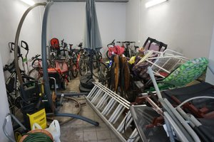 Garaż wypełniony skradzionymi przedmiotami. Na pierwszym aluminiowa drabina i meble ogrodowe. W tle widoczne rowery i kosiarki.