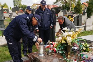 Policjanci zapalają znicz na grobie sierżanta Grzegorza Załogi zastrzelonego podczas wykonywania czynności służbowych.