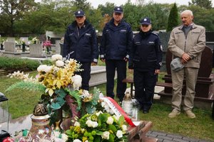 Policyjna delegacja razem z ojcem sierżanta Grzegorza Załogi stoją przed grobem.