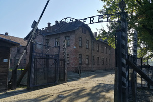 Wizyta w miejscu pamięci Auschwitz. Na zdjęciu widoczna brama wjazdowa i nad nią napis: Arbeit macht frei.