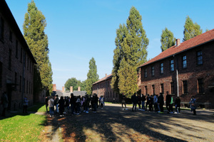 Wizyta w miejscu pamięci Auschwitz. Na zdjęciu widoczna młodzież stojąca pomiędzy budynkami.