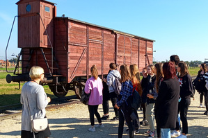Wizyta w miejscu pamięci Auschwitz. Na zdjęciu widoczna młodzież z przewodniczką. W tle wagon.