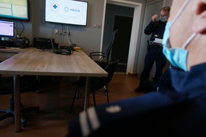 Na zdjęciu widoczny umundurowany policjant oraz wyświetlony początkowy slajd prezentacji na ekranie telewizora.