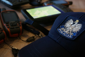 Na zdjęciu widoczna policyjna czapka, w tle włączony GPS i inne urządzenia.