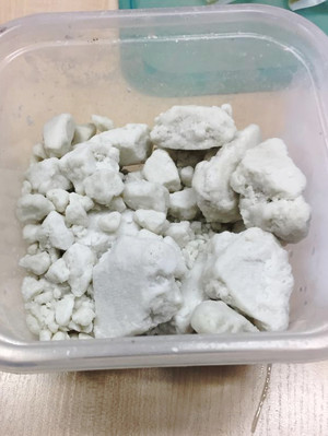 Widoczne kryształy białej substancji - amfetaminy, w plastikowym pojemniku