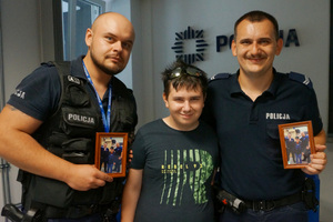 Na zdjęciu od lewej sierżant sztabowy Damian Seliga, Mikołaj i starszy sierżant Konrad Kluza. Policjanci trzymają w rękach pamiątkowe zdjęcia w ramkach.