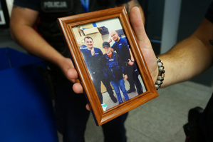 Trzymane w ręku zdjęcie, na którym widoczny jest starszy sierżant Konrad Kluza, Mikołaj oraz  sierżant sztabowy Damian Seliga.