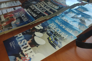 Na zdjęciu widoczne rozłożone na stoliku ulotki i gazety policyjne.