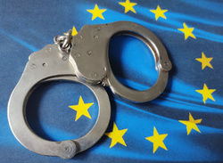 Na zdjęciu widoczna flaga Unii Europejskiej, na której leżą kajdanki.
