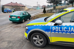 Na zdjęciu widoczny częściowo radiowóz oraz policjant stojący przy samochodzie.