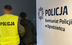 Na zdjęciu widoczny nieumundurowany policjant w kamizelce odblaskowej z napisem Policja oraz zatrzymany mężczyzna.