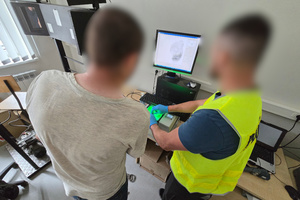 Na zdjęciu widoczny technik kryminalistyki, który skanuje linie papilarne zatrzymanego mężczyzny.