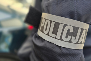 Na zdjęciu widoczna opaska z napisem POLICJA na ramieniu policjanta.