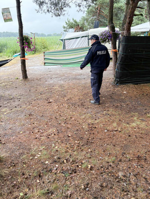 Na zdjęciu widoczny policjant, podczas kontroli wypoczywających na terenach zalesionych osób.