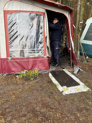 Na zdjęciu widoczny policjant, podczas kontroli wypoczywających na terenach zalesionych osób.