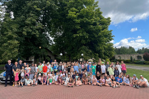 Zdjęcie grupowe, na którym widoczni są policjanci, strażak oraz biorąca w spotkaniu młodzież i dzieci.