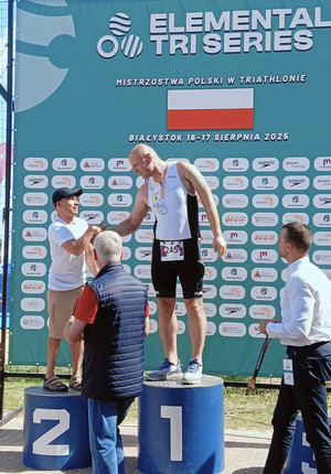 Na zdjęciu widoczny Zbigniew Adamowski na podium odbiera gratulacje i medal.