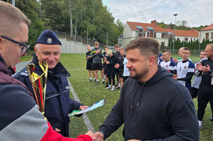 Na zdjęciu widoczny Pierwszy Zastępca Komendanta Powiatowego Policji w Zawierciu podinspektor Paweł Sobota, który wręcza puchar zawodnikowi.