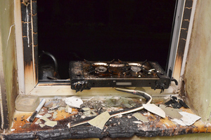 Na zdjęciu widoczne otwarte okno oraz parapet, które noszą ślady palenia. Na parapecie stoi elektryczna maszynka do gotowania.