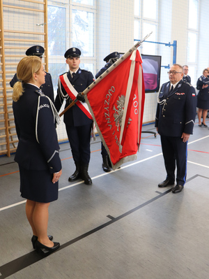 Na zdjęciu widoczny poczet sztandarowy ze sztandarem, po którego lewej stronie stoi młodszy inspektor Renata Hałabuda, a po prawej inspektor Artur Klimek.