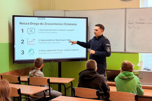 Na zdjęciu widoczny policjant oraz uczniowie podczas prelekcji.