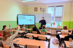 Na zdjęciu widoczny policjant oraz uczniowie podczas prelekcji.