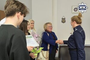 Delegacja Zespołu Szkół w Porębie wręcza Komendantowi Powiatowemu Policji w Zawierciu młodszemu inspektorowi Renacie Hałabudzie pamiątkowe gratulacje oraz kwiaty. Pani dyrektor Elżbieta Horbatowska składa gratulacje.