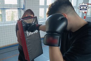 Nieumundurowany policjant uderza ręką w rękawicy w tarczę ochronną trzymaną przez innego nieumundurowanego funkcjonariusza.