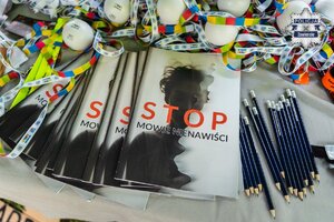 Leżące na stoliku gadżety, w tym broszura "Stop mowie nienawiści".
