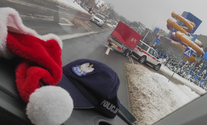 Na zdjęciu widać policyjną czapkę na podszybiu, a w tle samochód Straży Pożarnej z przyczepką