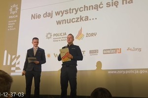 Na zdjęciu widać przedstawiciela Urzędu Miasta Żory oraz policjanta. Policjant trzyma w dłoni mikrofon.