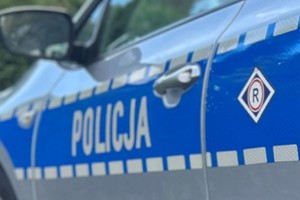 Na zdjęciu widać bok radiowozu z napisem Policja oraz emblematem ruchu drogowego.