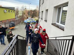 Na zdjęciu widać policjantów oraz osoby przebrane w kolorowe stroje wchodzących po schodach.