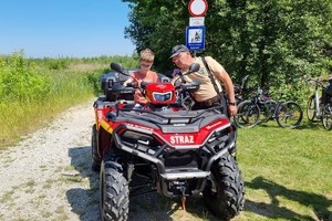 Na zdjęciu widać strażackiego quada oraz uczestników pikniku.