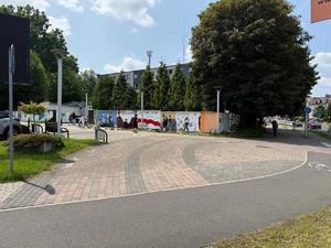 Na zdjęciu widać galerię murali podczas ich tworzenia, a także uczniów i zgromadzonych podczas akcji pod nazwą &quot;Plenerowa lekcja patriotyzmu&quot;.