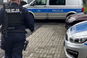 Na zdjęciu widać policjanta i policyjne radiowozy.