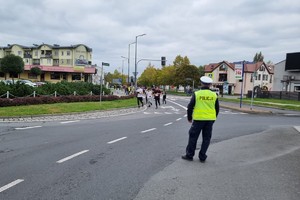 Na zdjęciu widać radiowóz, a w tle uczestników biegu.