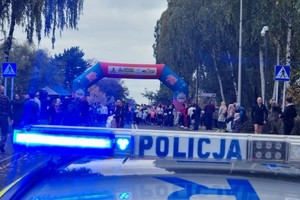 Na zdjęciu widać radiowóz, a w tle uczestników biegu.