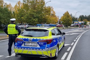 Na zdjęciu widać radiowóz, a w tle uczestników biegu.
