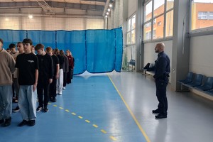 Na zdjęciu widać policjanta oraz uczniów podczas zajęć musztry.
